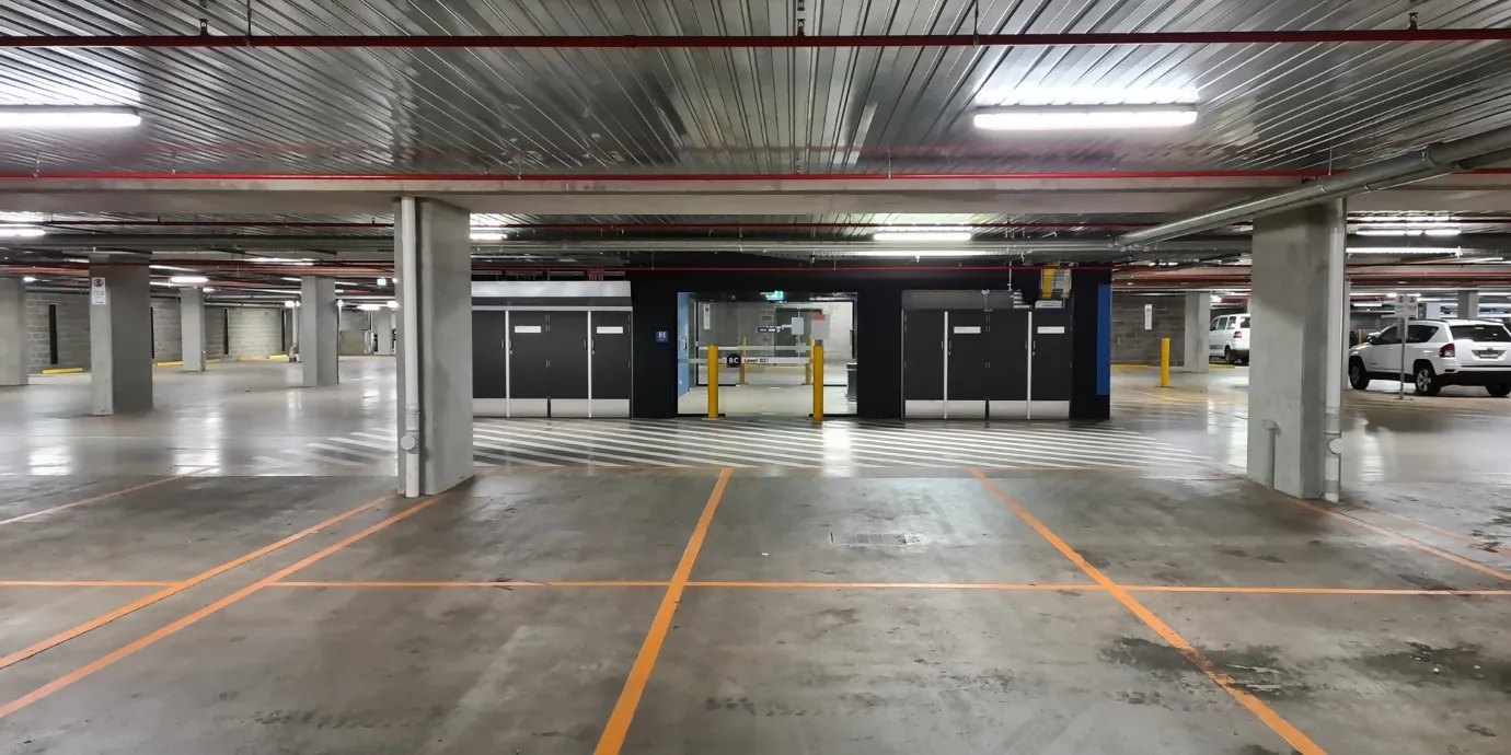 Empty car park with clearly visible ceiling lighting that evenly illuminates the entire area