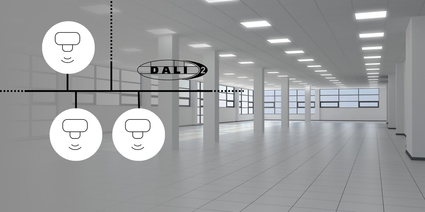 Leere, in weiss gehaltene und gut beleuchtete Bürohalle, links oben drei Sensoren mit DALI-Netzwerk verbunden