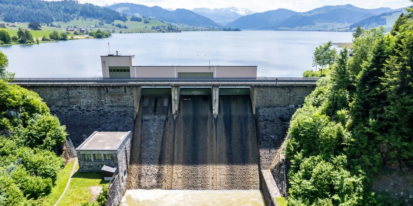 Luftaufnahme auf den Sihlsee, im Hintergund die Berge im Vordergrund die Staumauer