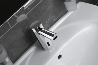 Silver, shiny tap on a grey-white washbasin