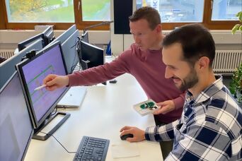 Zwei Mitarbeiter vor einem Bildschirm bei der Überprüfung von Daten eines Produktes