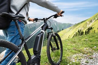 Person schiebt ein e-Bike auf einer Naturstrasse in einer Bergregion