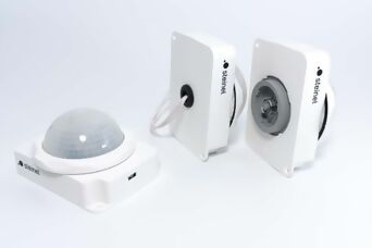 Drei weisse Highbay Sensoren auf hellgrauem Hintergrund. Von einem Sensor ist die Linse gut abgebildet und von den anderen zwei sind die Anschlussvarianten zu sehen.