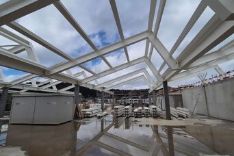 A photograph of the interior of the new building, with its roof open and the sky reflected on the rain-soaked floor