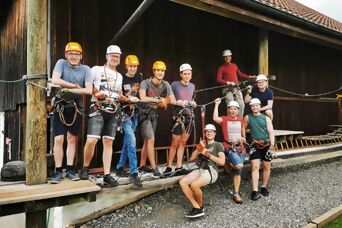Eine Gruppe von Auszubildenden mit Kletterausrüstung und Helmen im Seilpark