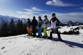 Fünf Personen in Skiausrüstung bei einem Schönwetter-Skitag