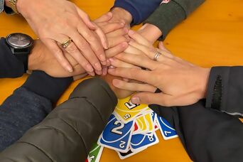 Viele Hände über einem Stapel gespielter Uno-Karten