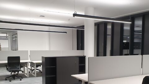Empty office with modern office furniture and linear fluorescent light fixtures on the ceiling