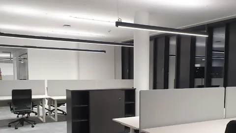 Empty office with modern office furniture and linear fluorescent light fixtures on the ceiling