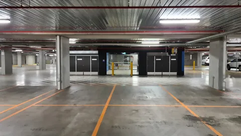 Empty car park with clearly visible ceiling lighting that evenly illuminates the entire area