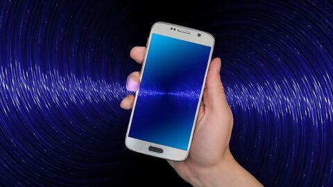Hand hält Smartphone, eingezeichnete blaue Funkwellen
