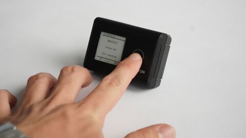 schwarzes Gerät, IOX Button, mit einer Hand, welche den Knopf drückt