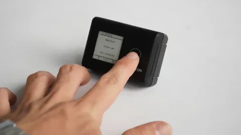schwarzes Gerät, IOX Button, mit einer Hand, welche den Knopf drückt