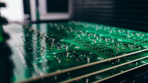 Nahaufnahme von grüner Leiterplattte in Rack mit Elektronikbauteilen
