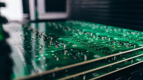 Nahaufnahme von grüner Leiterplattte in Rack mit Elektronikbauteilen