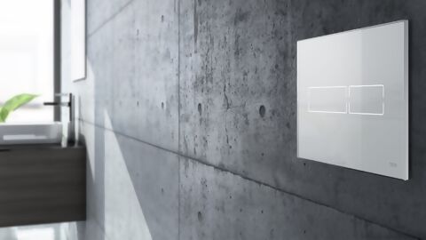 Helle, kontaktlose Spülbetätigungsplatte an einer dunklen Granitwand in Badezimmer