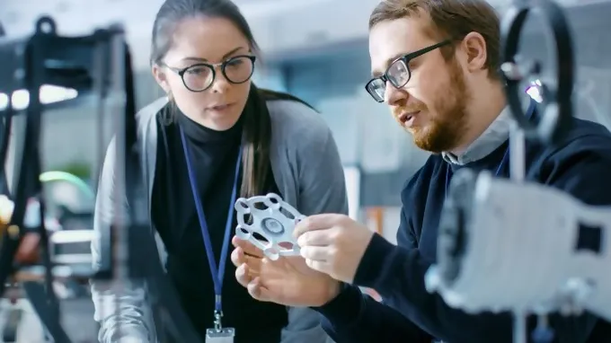 Eine Frau und ein Mann besprechen ein Produkt vor Industriehintergrund
