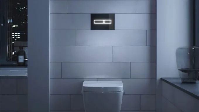 Black Tece Lux Mini toilet flush plate on grey concrete wall in bathroom
